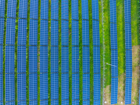 Aerial view of rows of blue solar panels installed on a lush green field under bright daylight Guanaja, Bay Islands Department, Honduras.