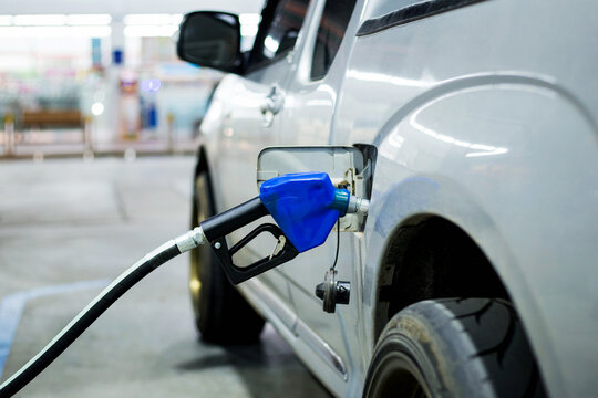 Blue fuel nozzle fueling a car in gasoline stations.