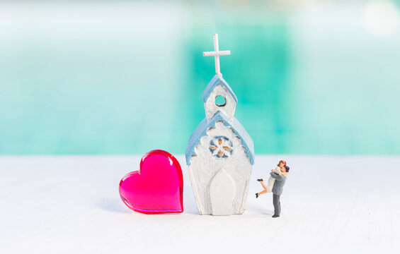 Miniature couple with red heart and church over blurred background, love and romance, valentine background idea