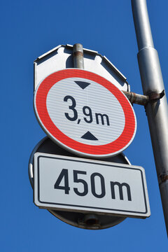 A round height limit traffic sign showing three point nine meters is mounted above a rectangular plate indicating a distance of four hundred fifty meters