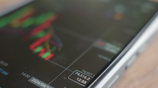 Close up of smartphone screen with candlestick trading chart and price data. Bitcoin price movement in mobile trading app. Concept of cryptocurrency volatility market analysis and digital investment