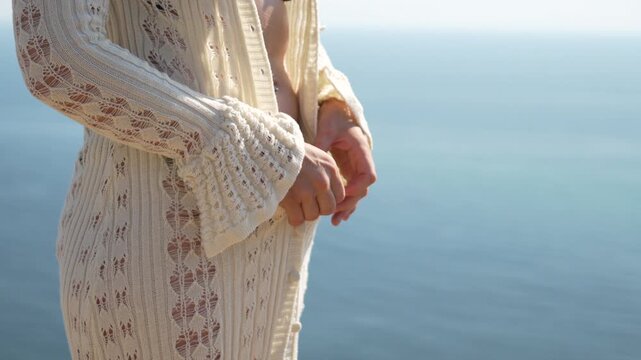Woman cardigan ocean, unbuttoning white knitwear on sunny day by the sea