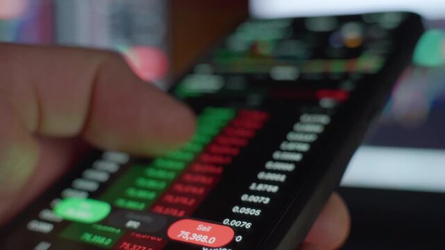 Close up of finger using smartphone with trading app and sell order on screen. Concept of mobile investing digital finance market activity and fintech technology.
