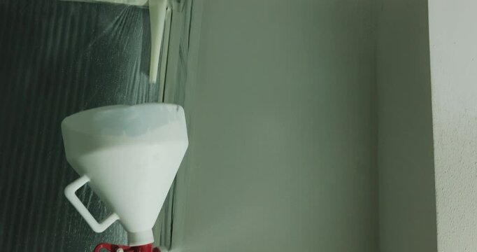 Spraying paint onto wall with spray gun during interior finishing close up