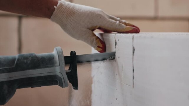 Cutting aerated concrete block with reciprocating saw during construction close up