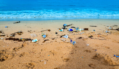 The sand beach with  beautiful turquoise beach polluted with a large pile of plastic waste and garbage  concept of ocean pollution, environmental crisis, and the impact on marine ecosystems. © SASITHORN