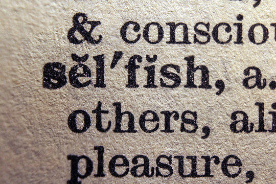 Word selfish on dictionary page, macro close up