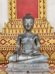 Fototapeta premium Tranquil Buddha Statue: A serene Buddha statue sits in meditative repose, exuding a sense of peace and contemplation against the backdrop of an intricately designed temple setting.