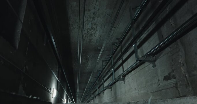 View down elevator shaft with cables and guide rails perspective