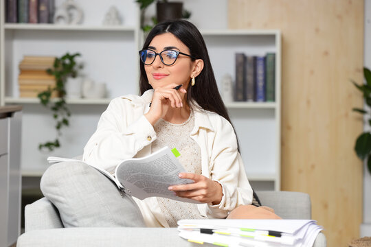 Female screenwriter with script sitting on sofa in office