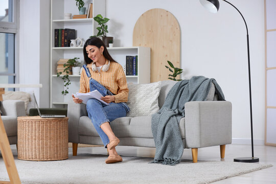 Female screenwriter with script sitting on sofa in office