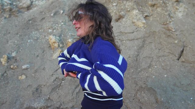 Woman sweater cliffside middle aged lady in a striped knit pullover enjoys a breezy day and picks up a pink jacket