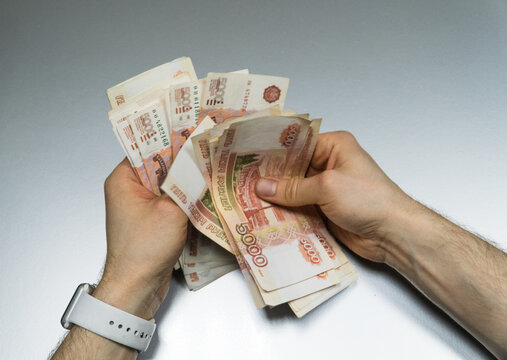 Man counts red paper 5000 rubles bills. Russian cash money in male hand. A man holds a wad of money in his hands. A close-up of a man's hands counts a bundle of bills for five thousand Russian rubles.