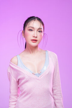 Beautiful young Asian woman with glowing skin and trendy wet hair look posing against a pastel pink background; elegant fashion portrait showcasing skincare, facial treatment, and Gen Z aesthetic.