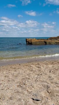 Serene Sandy Beach with Small Waves and Rocky Formation