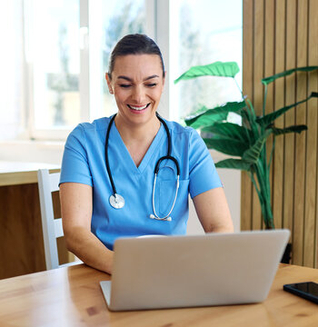 Portrait of a young nurse getting ready for work and using laptop online meeting at home. Overworked, busy, stress, urgency, multitasking concepts