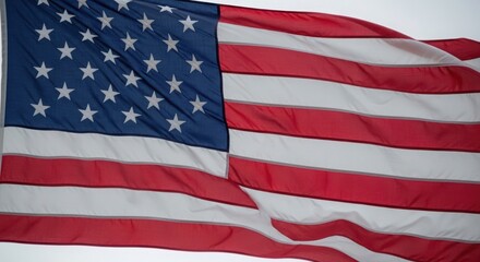 Obraz premium American flag waving in wind on cloudy day - patriotic USA symbol for national holidays and freedom