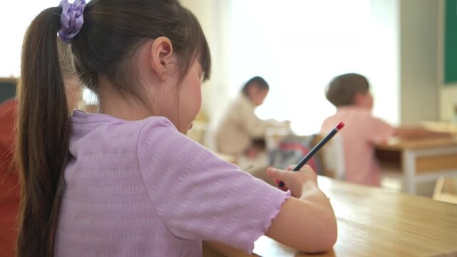 The student is taking notes while being taught by the teacher in the classroom, demonstrating a positive and attentive learning atmosphere in an international school