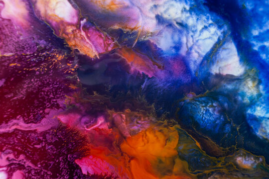 Colorful abstract art created with paint on a surface, showing deep blue and bright orange blending in unique shapes, captured in a studio setting