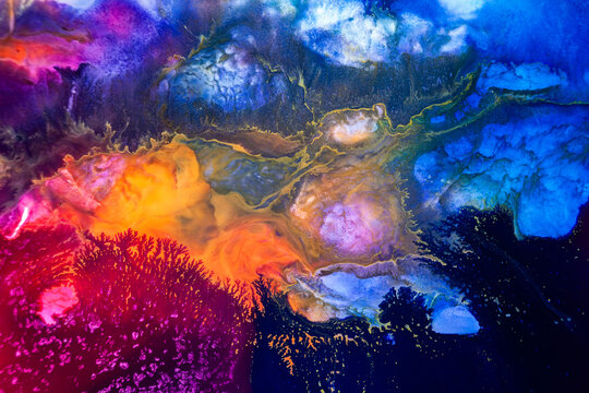 Colorful abstract art created with paint on a surface, showing deep blue and bright orange blending in unique shapes, captured in a studio setting