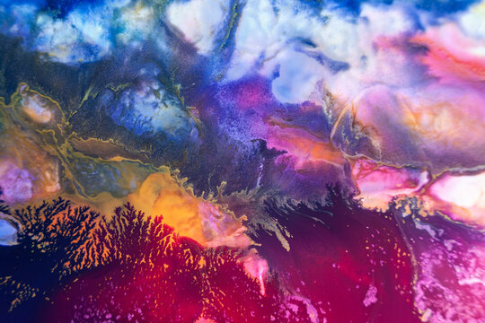 Colorful abstract art created with paint on a surface, showing deep blue and bright orange blending in unique shapes, captured in a studio setting
