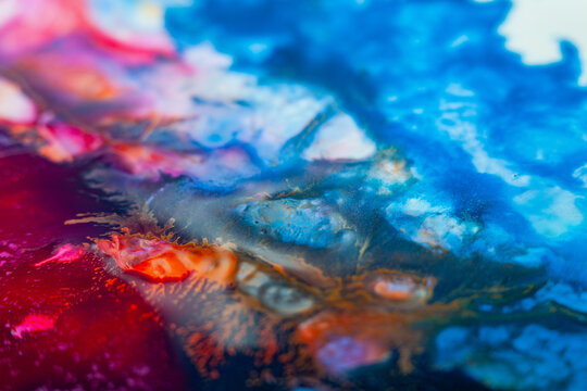 Colorful abstract art created with paint on a surface, showing deep blue and bright orange blending in unique shapes, captured in a studio setting