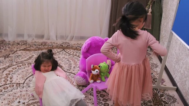 Kyrgyz Asian girls playing school at home, one child acting strict teacher while another lying and ignoring lesson, disobedient behavior, discipline problem, childhood interaction and education