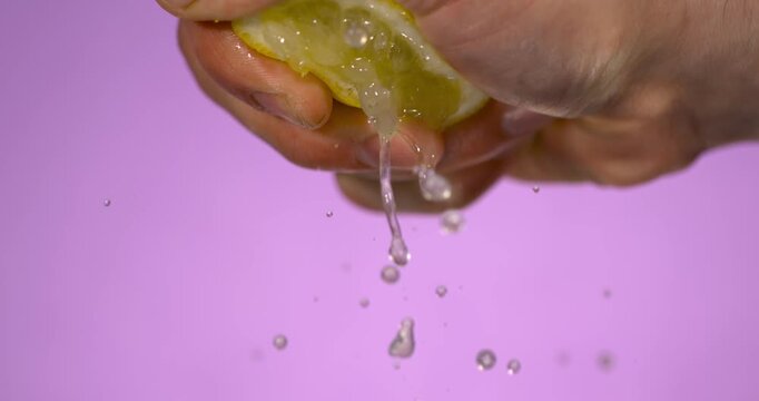 Super Slow Motion Caucasian Hand Squeezing Lemon Over Purple Backdrop, Slow