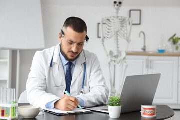 Fototapeta premium Male doctor in AR glasses writing on clipboard at office