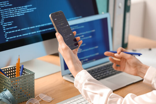 Female programmer's hands working with mobile phone in office, closeup
