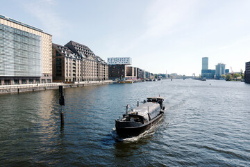 Freight barge sailing on Berlin Spree River with waterfront buildings and skyscraper © Jarama