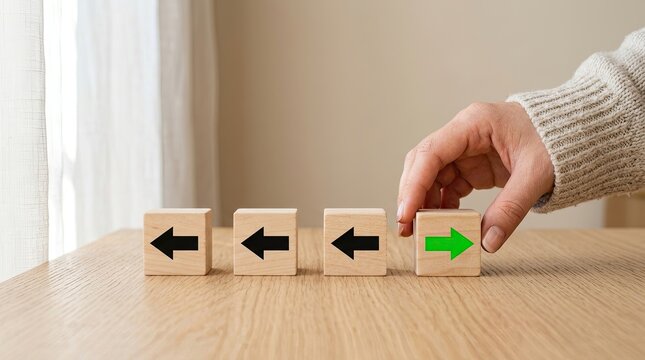 A hand places a wooden block with a green arrow among blocks pointing left