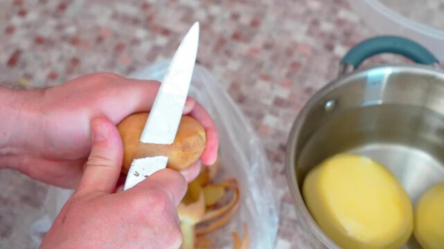 Person Peeling Potatoes with Knife Close-Up Food Preparation in Kitchen 4K