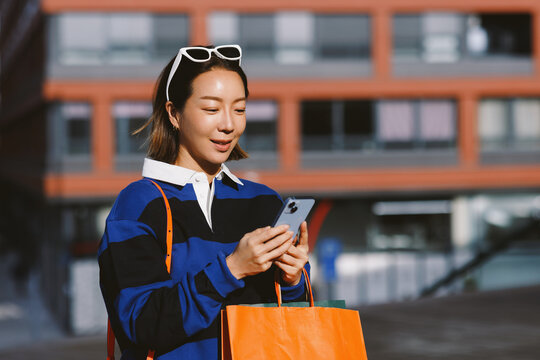 Asian woman shopping online using smartphone in city