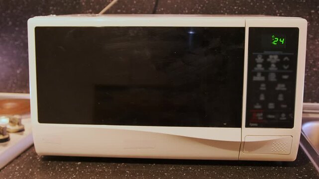 microwave oven running with timer on display close-up, appliance heating food inside during cooking cycle, everyday kitchen process for quick meal preparation and home use