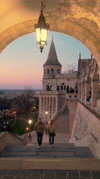 Couples wander hand in hand along the enchanting pathways of Fishermans Bastion, surrounded by historic architecture and breathtaking views of Budapest during dusk.