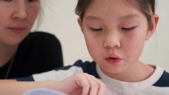 Young girl struggles to understand homework while mother calmly explains lesson, supportive learning environment with slight difficulty, focused study process in Kyrgyz Asian family home