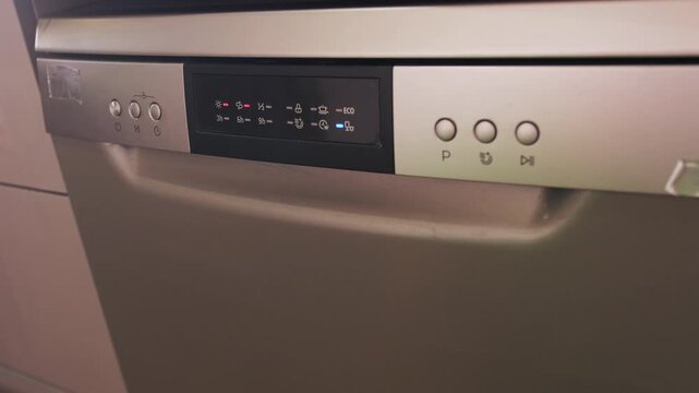 Dishwasher control panel close-up as washing program starts, digital display and buttons activated, modern kitchen appliance interface, automation cleaning cycle in home environment