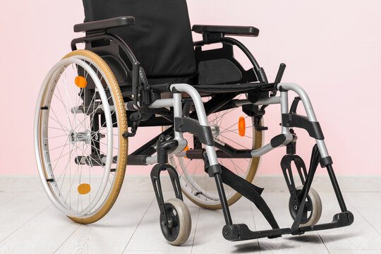 Empty wheelchair near pink wall