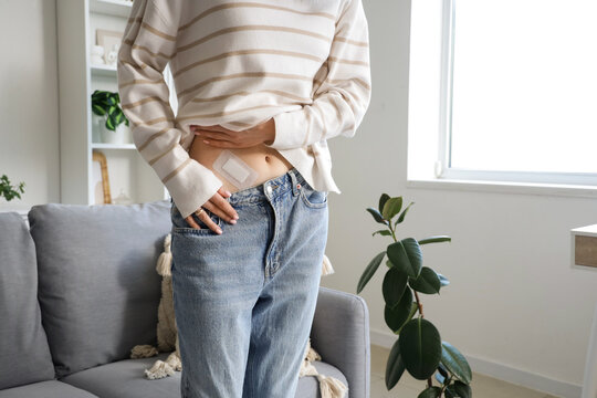 Young woman with applied medical patch after appendectomy surgery at home, closeup