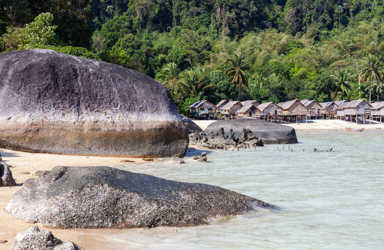 Moken Sea Gypsy Village on Koh Surin, Thailand. Tropical island setting with traditional huts. Clear blue water and beach.
