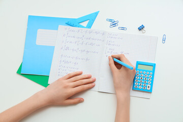 Fototapeta premium Woman writing math formulas in copybook on light background