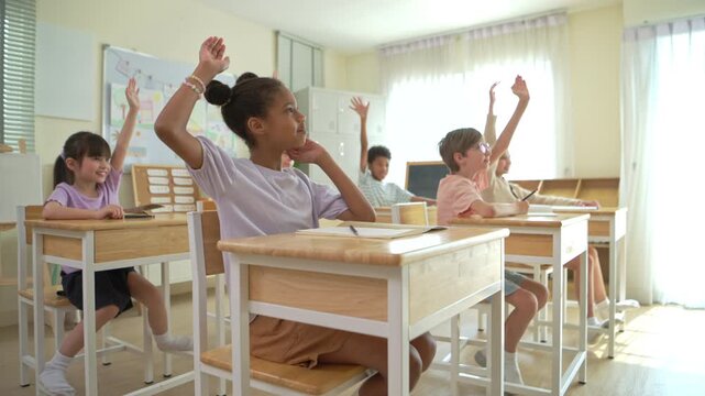 Group of students raising hands eagerly in classroom, representing active participation and engaging learning environment