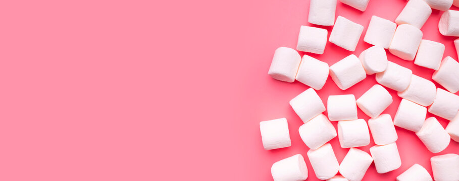 Scattered marshmallows on pink background flat lay top view. Sugar candies, sweet abstract background. Delicious dessert, pastel soft shades. Space for text