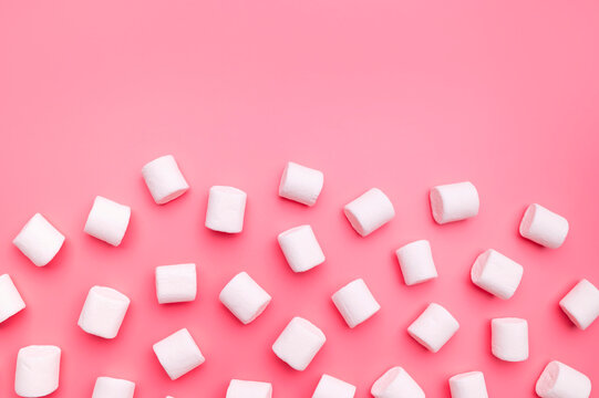 Scattered marshmallows on pink background flat lay top view. Sugar candies, sweet abstract background. Delicious dessert, pastel soft shades. Space for text