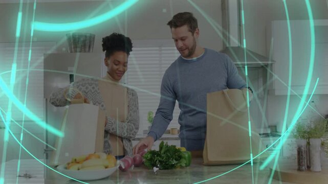 Couple opening grocery bags in kitchen, placing produce for meal while teal ring graphic overlaying