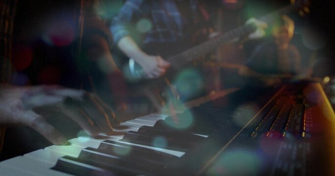Playing female keyboardist pressing synth keys at small stage, wearing dark sleeves, lit sliders