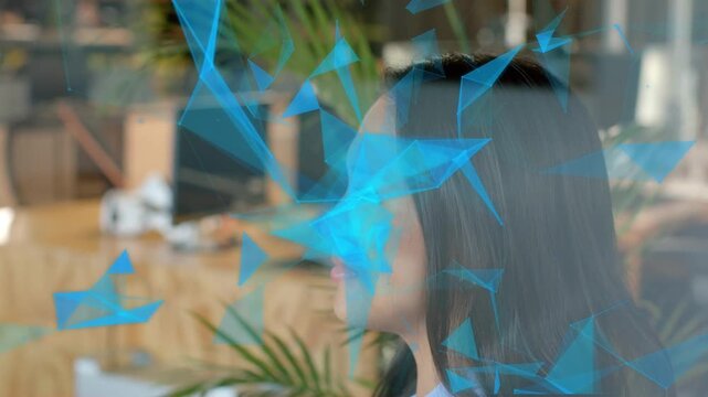 Woman sitting in business office, reacting to blue triangular mesh drifting across face and smiling