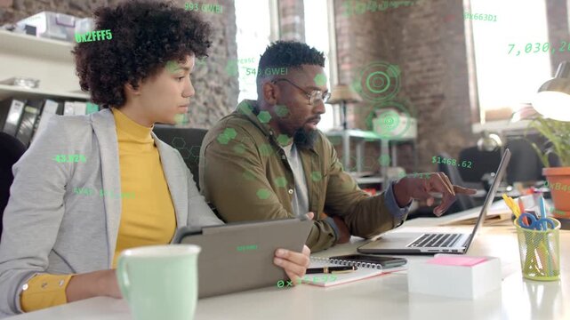 Man pointing laptop, initiating tech data walkthrough while woman studying tablet with green HUD