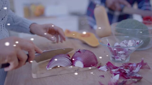 Cook bringing knife slicing red onion on board preparing for cooking with white sparkles floating